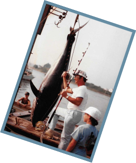 Old photo of a man and boy wearing classic saltwater fishing apparel with their prize catch