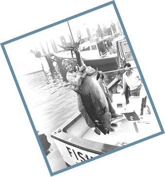 Someone hanging from a caught fish wearing early fishing brands clothing